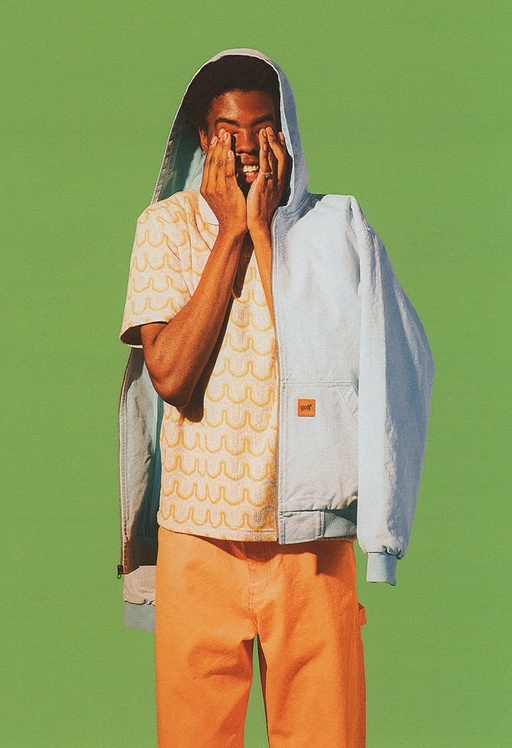 A man wearing a Golf Wang baby blue jacket and an orange button up with matching pants