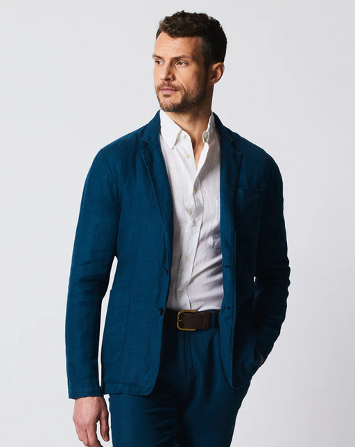 A man wearing a Billy Reid navy blue suit and white button up shirt