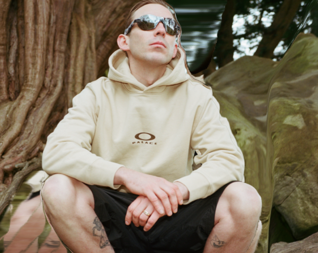 A man wearing Oakley sunglasses and branded hoodie