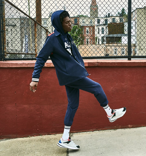 A man wearing a Under Armour navy blue outfit with white sneakers