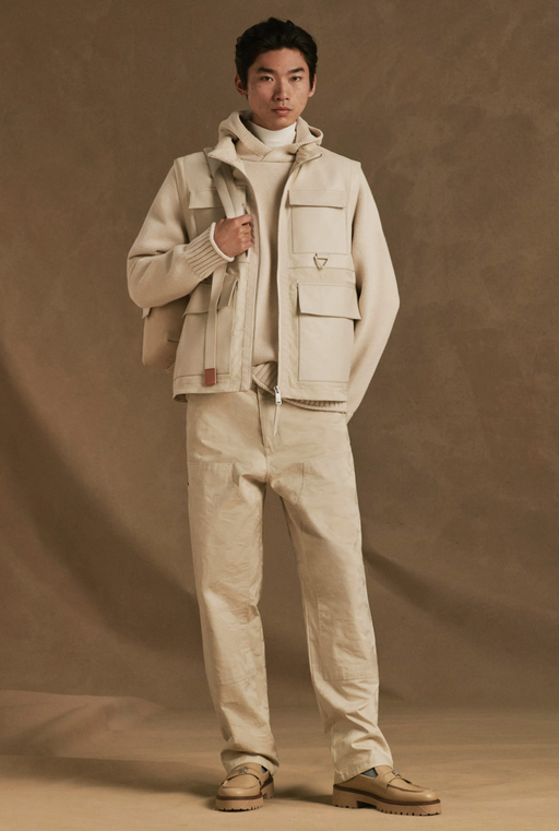 A man wearing a beige Tommy Hilfiger outfit with a vest, hoodie and pants