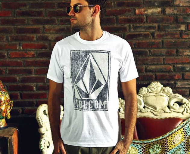 A man wearing a Volcom logo icon t-shirt in white and sunglasses