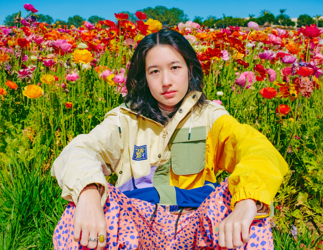 A womman wearing The Quiet Life outfit sitting amidst a bed of roses