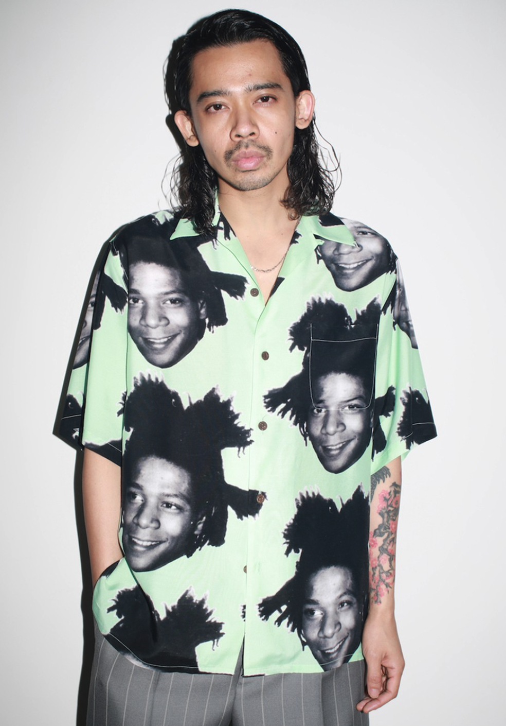 A man wearing a Wacko Maria Jean-Michel Basquiat all over print button up t-shirt