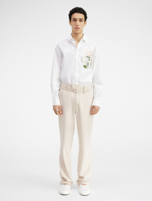 A man wearing a Jacquemus white shirt with a floral chest print and khaki pants