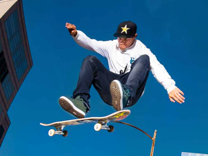 A man skateboarding while wearing green Etnies shoes