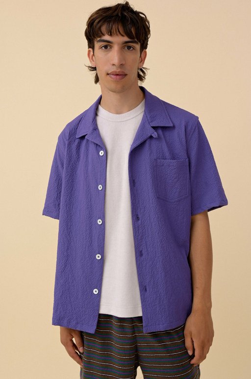 A man wearing a Purple Howlin' button up with a white t-shirt underneath