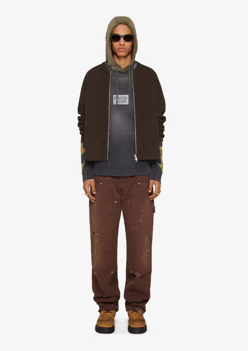 A man wearing a Givenchy outfit with a black jacket, hoodie and brown pants
