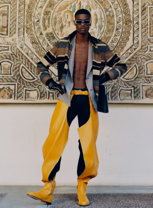 A man wearing a Loewe designer outfit with yellow pants and shoes and an open jacket
