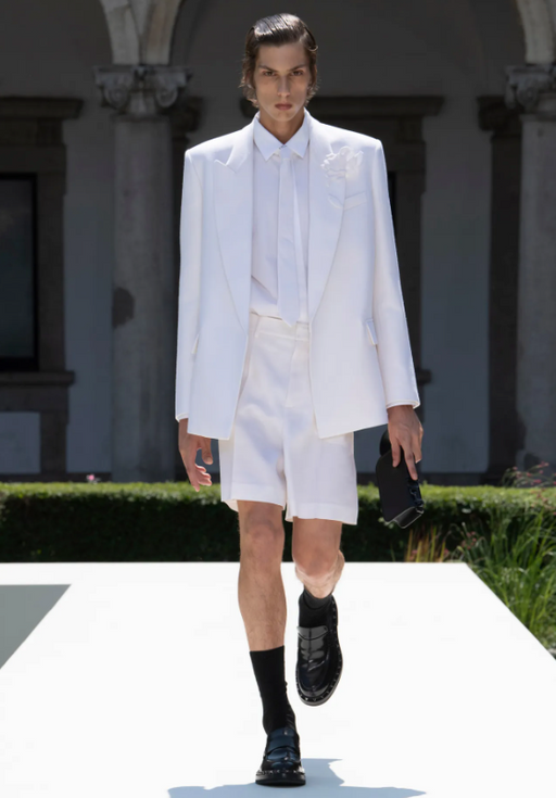 A man wearing a white Valentino suit with shorts