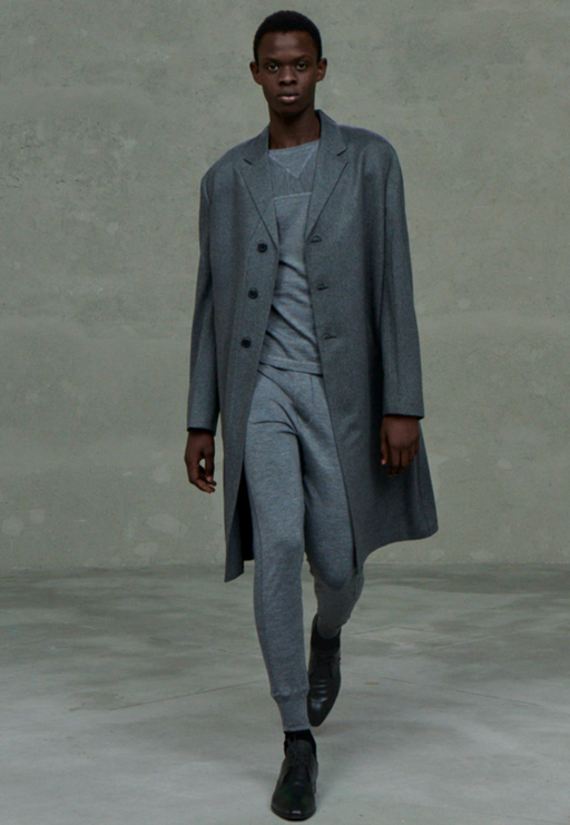 A man wearing a Prada outfit in dark grey with a long coat