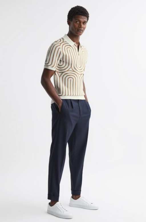 A man wearing a Reiss wavy striped collared shirt with navy blue pants