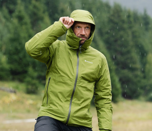 A man wearing a green Montane winter jacket with the hood on