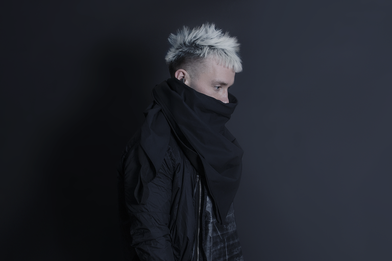 A man wearing a oversize AOKU black scarf and jacket