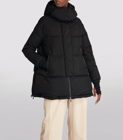 A man wearing a HERNO LAMINAR black long puffy jacket with beige pants
