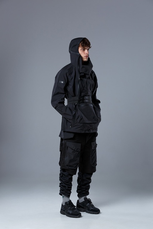 A man wearing a RIOT DIVISION black outfit featuring a technical jacket and pants