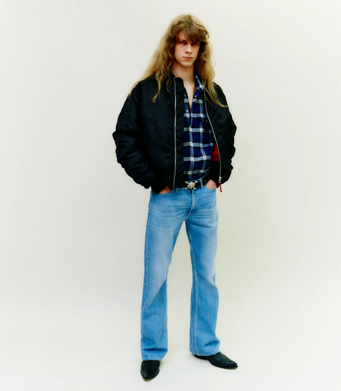 A man wearing a retro Stockholm Surfboard Club jacket, plaid and bell-bottomed jeans