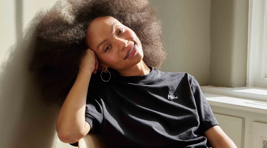 A woman wearing a black Maha logo t-shirt