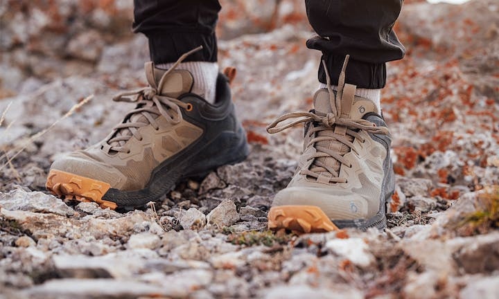 A man wearing a pair of brown and orange Oboz trail shoes