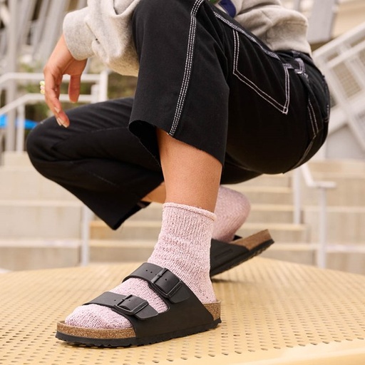A woman wearing a brown classic Birkenstocks with pink socks