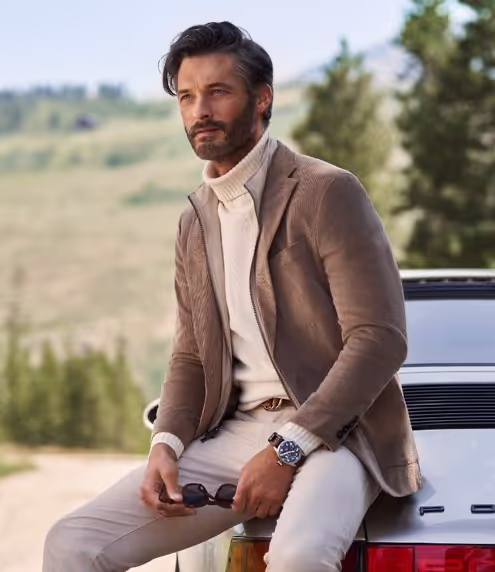 A man wearing a brown suit jacket and turtleneck