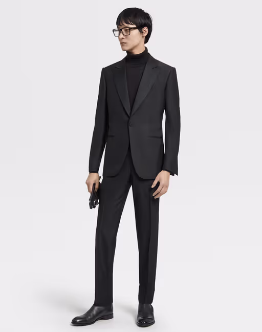 A man wearing an all black Zegna suit with a black turtleneck underneath