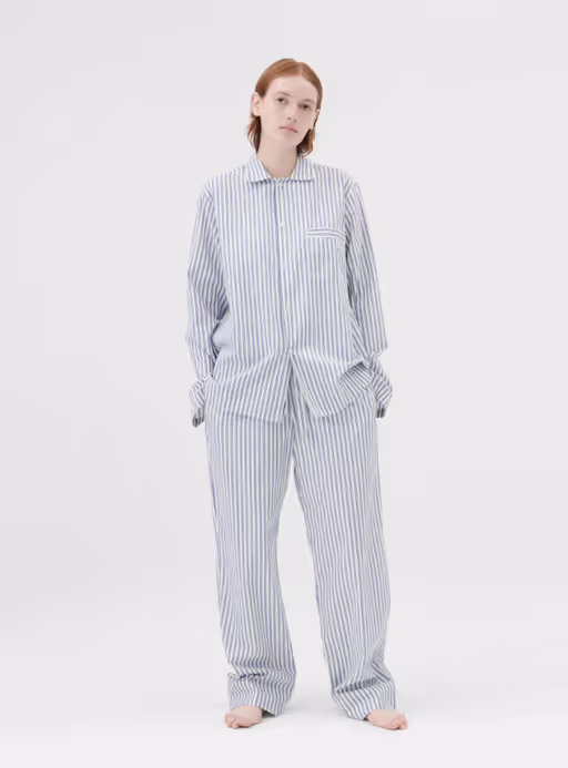 A woman wearing a Tekla pajama outfit in blue and white stripes
