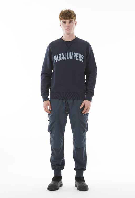A man wearing a Parajumpers logo sweater and navy blue pants