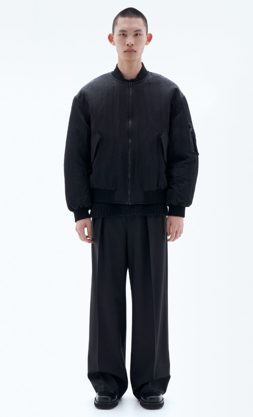 A man wearing a black Filippa K outfit with a jacket and baggy pants