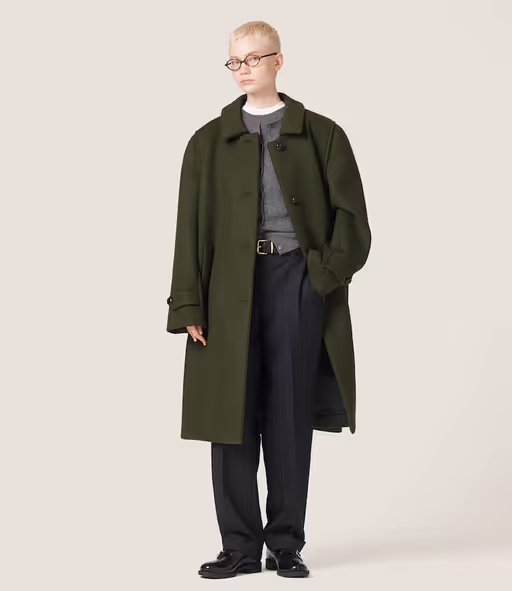 A woman wearing an oversize green trench coat by Miu Miu