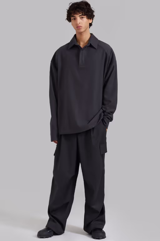 A man wearing a black 'The Frankie Shop' button-up and black pants