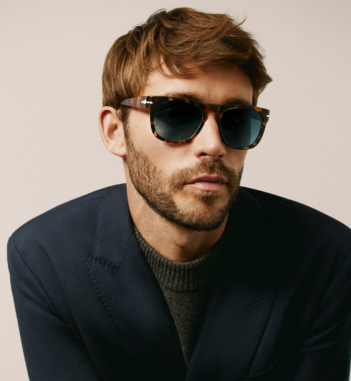 A man wearing oversize Persol sunglasses with a suit jacket