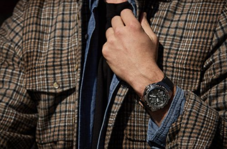 A man wearing a black Citizen Watch and a plaid jacket