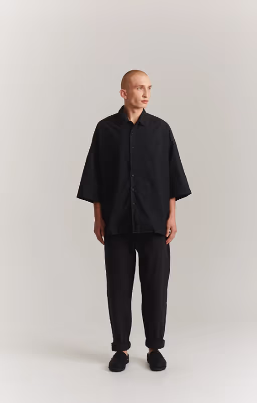 A man wearing a CASEY CASEY black oversize april shirt