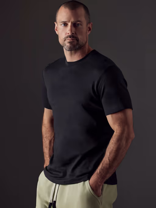 A man wearing a Aether Apparel black emery pima crew tee
