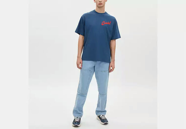A man wearing Coach dark denim boardwalk specials t shirt in organic cotton