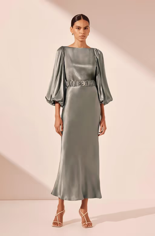 A woman wearing Shona Joy sage color la lune balloon sleeve midi dress with belt