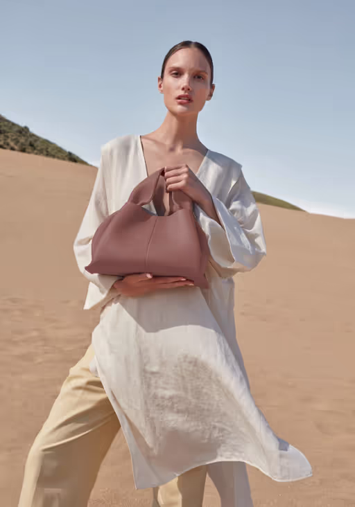 A woman carrying Polene numéro neuf edition blush grainé bag