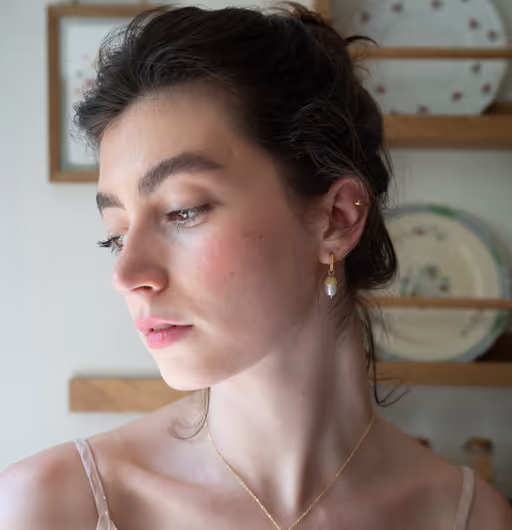 A woman wearing Fable England​ acorn pearl hoops earrings