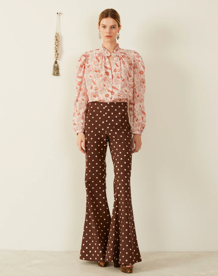 A woman wearing a Alix of Bohemian pink blouse and brown polka dot pants