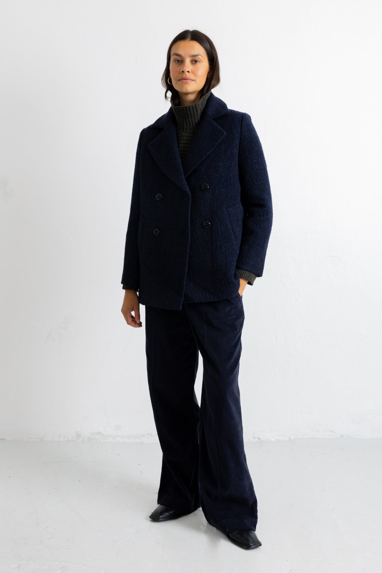 A woman wearing a navy textured wool Folk peacoat with matching wide-leg trousers