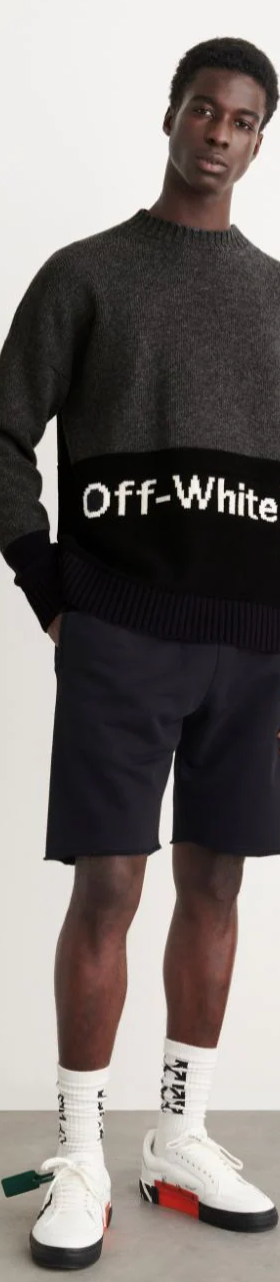 A man wearing a black Off-White sweater, black shorts and branded Off-white socks