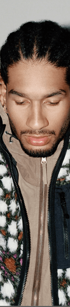 A man wearing a white and brown Stussy fleece with a brown jacket underneath